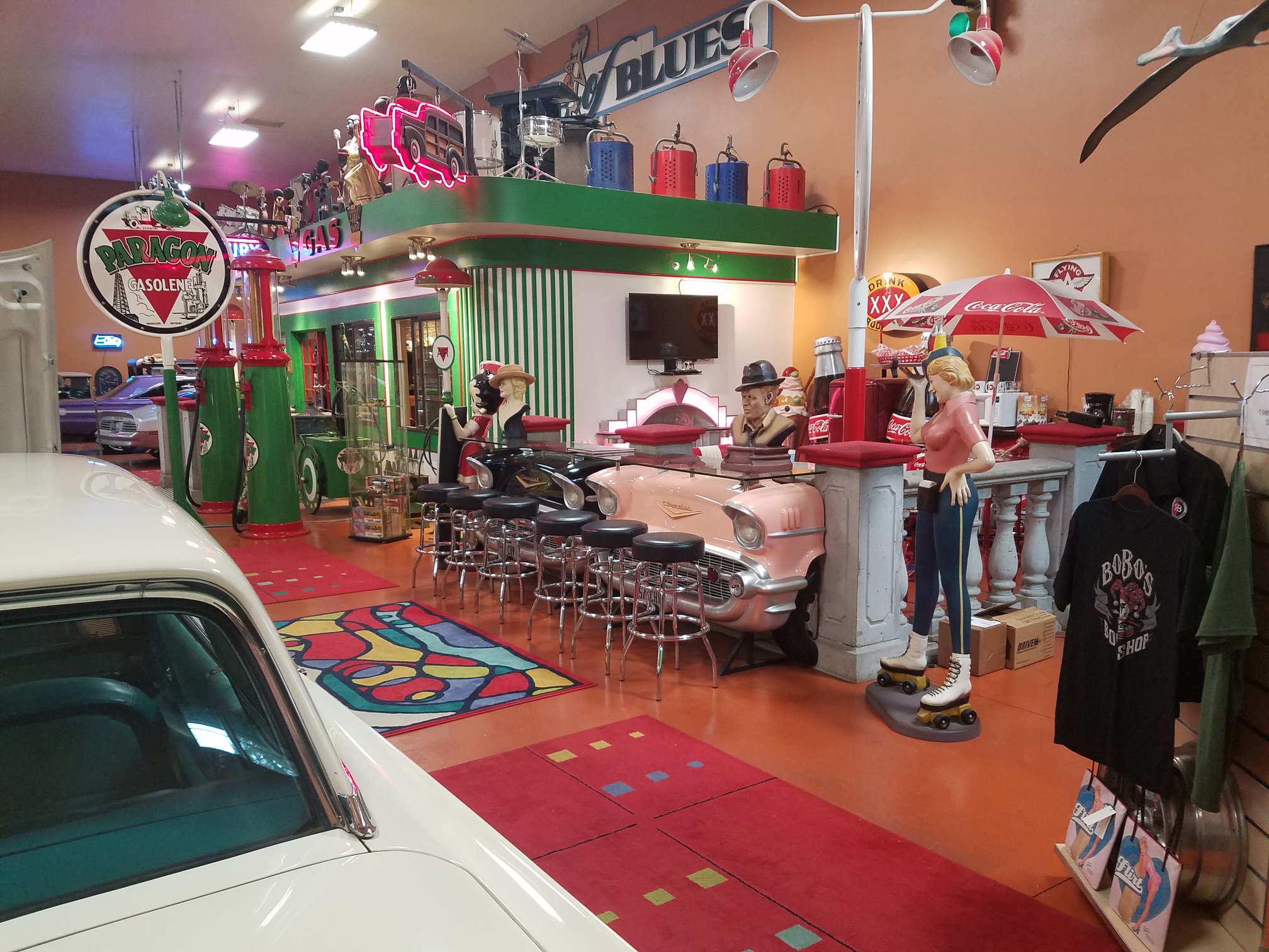 Retro diner display with car-front stools and vintage gas pumps