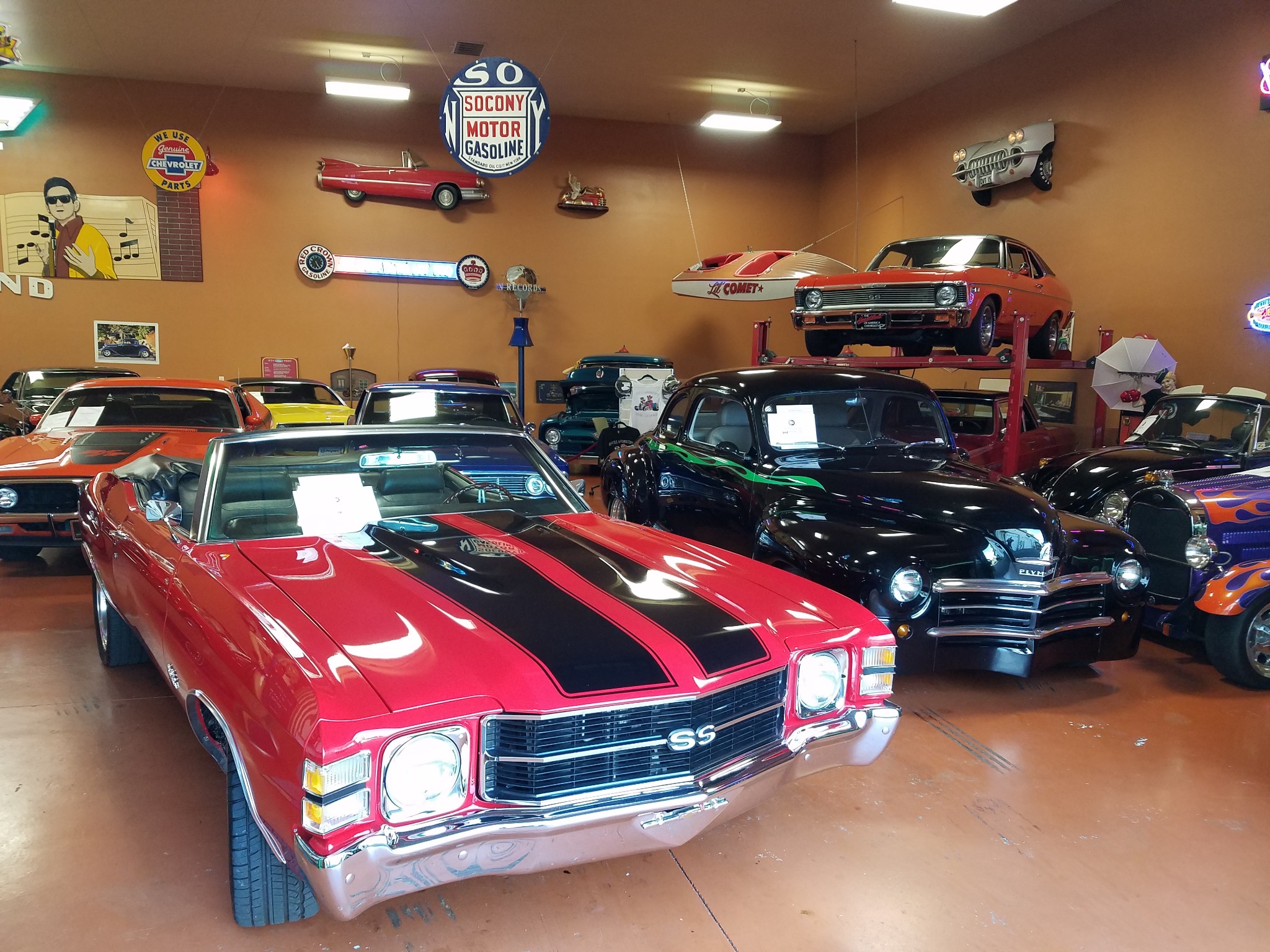 Red convertible and other classic muscle cars displayed indoors